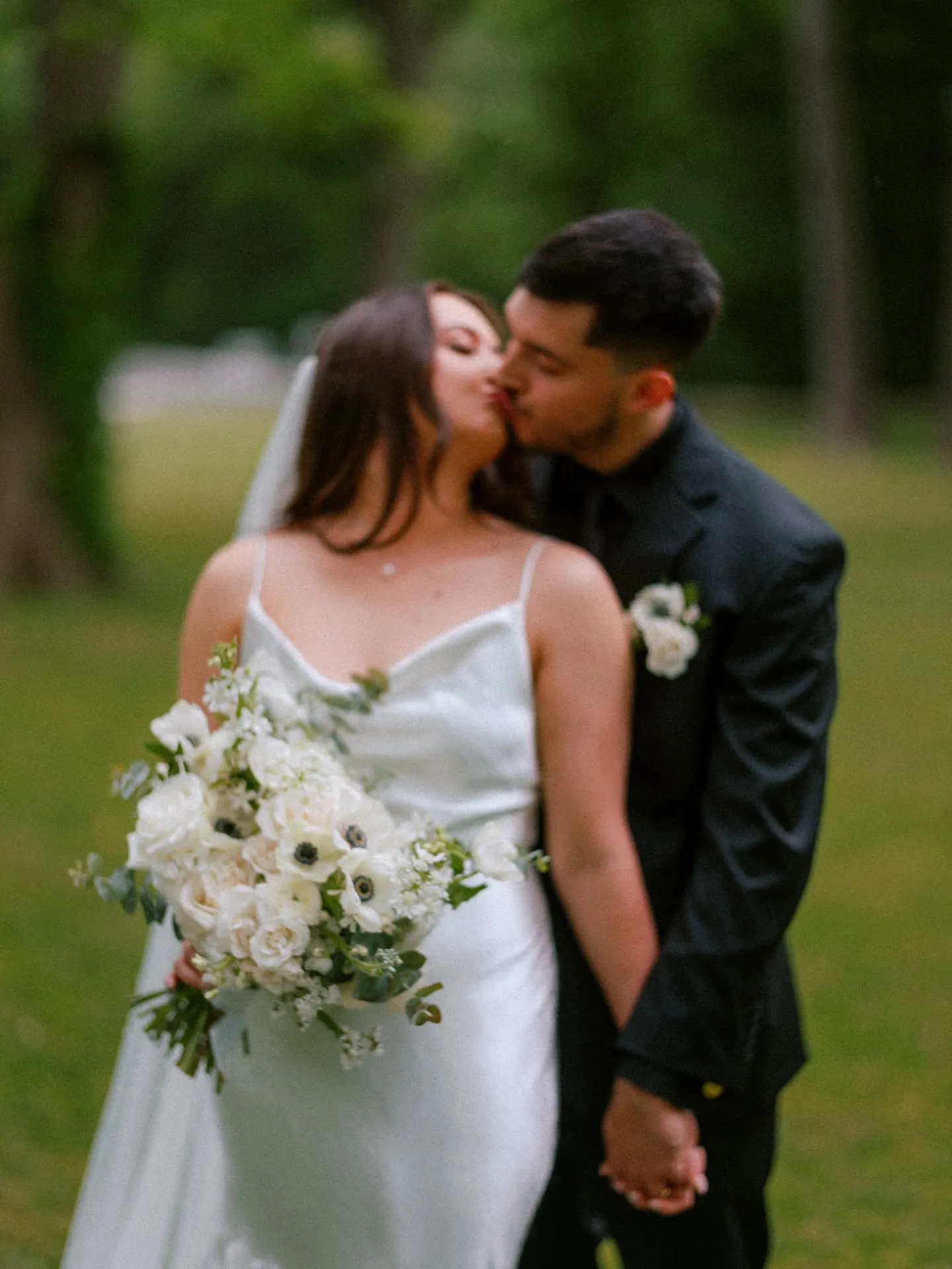 Couple kissing behind a white bouquet held in focus