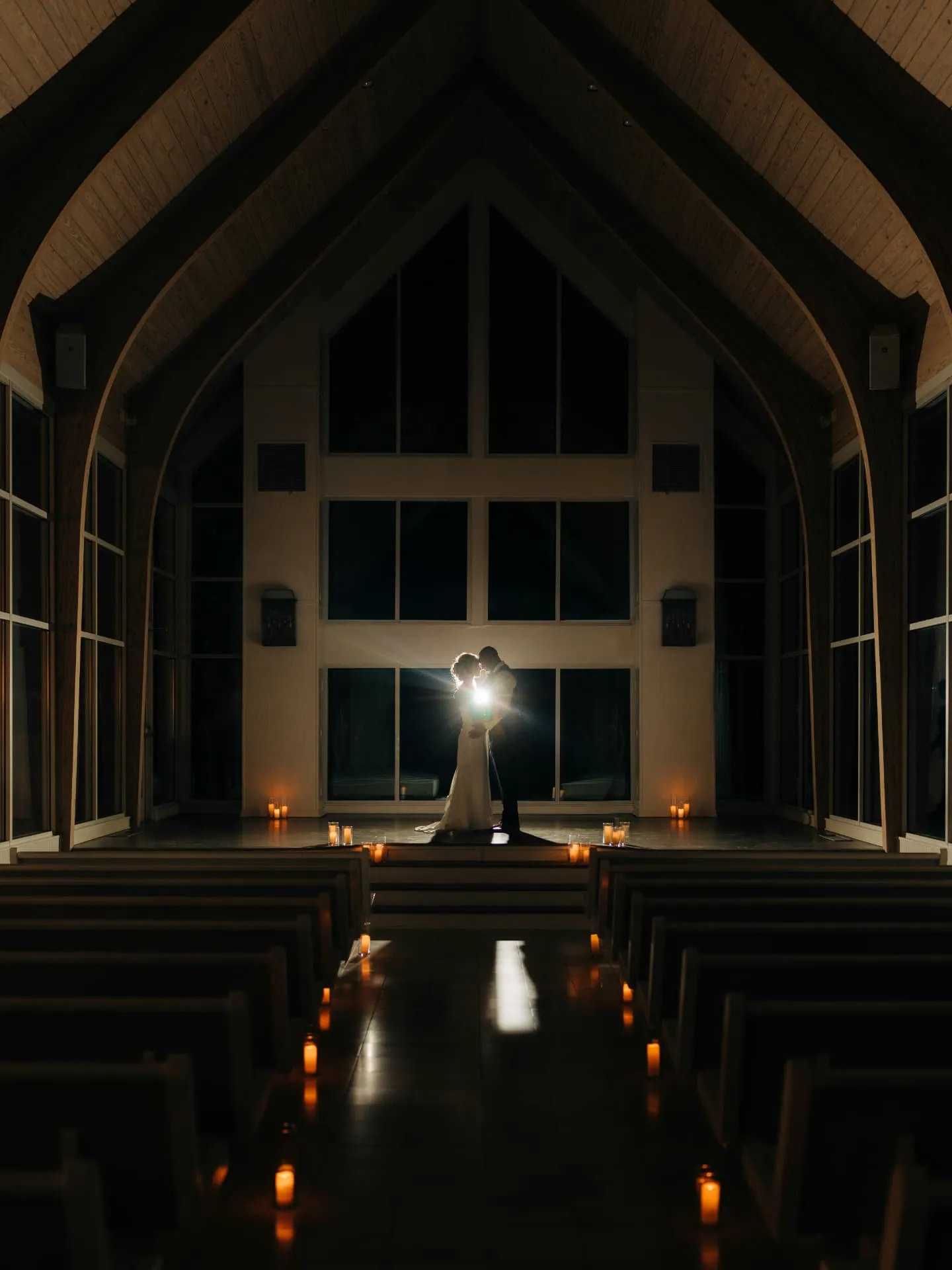 Couple backlit in a candlelit chapel at night
