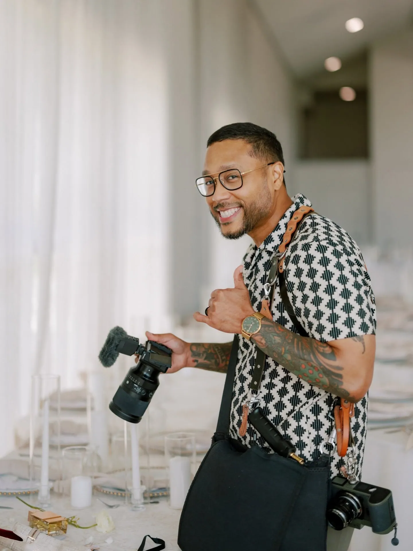 William Johnson at a wedding reception, camera in hand, smiling back at the lens