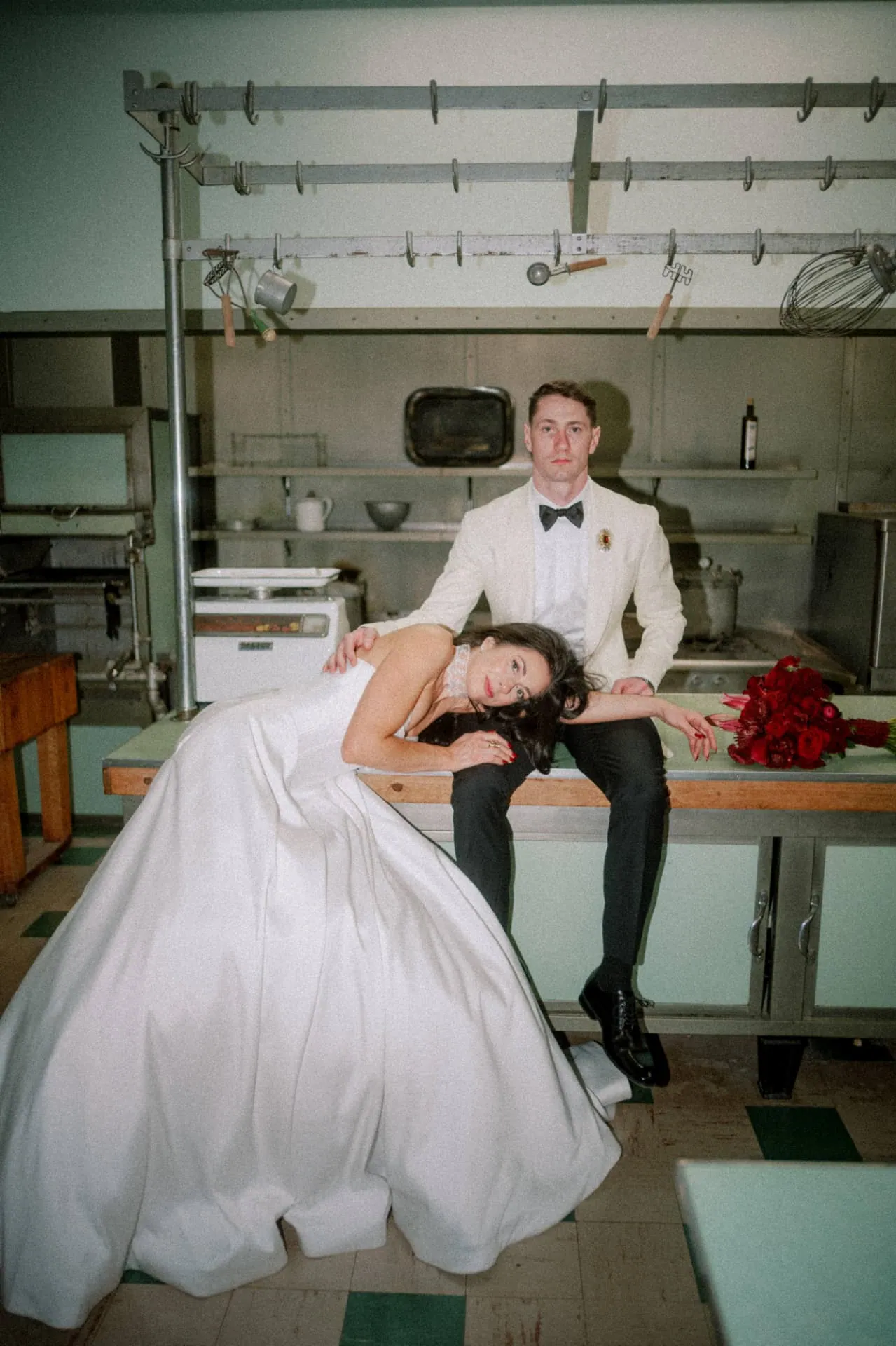 Couple posed in a vintage green kitchen with red roses