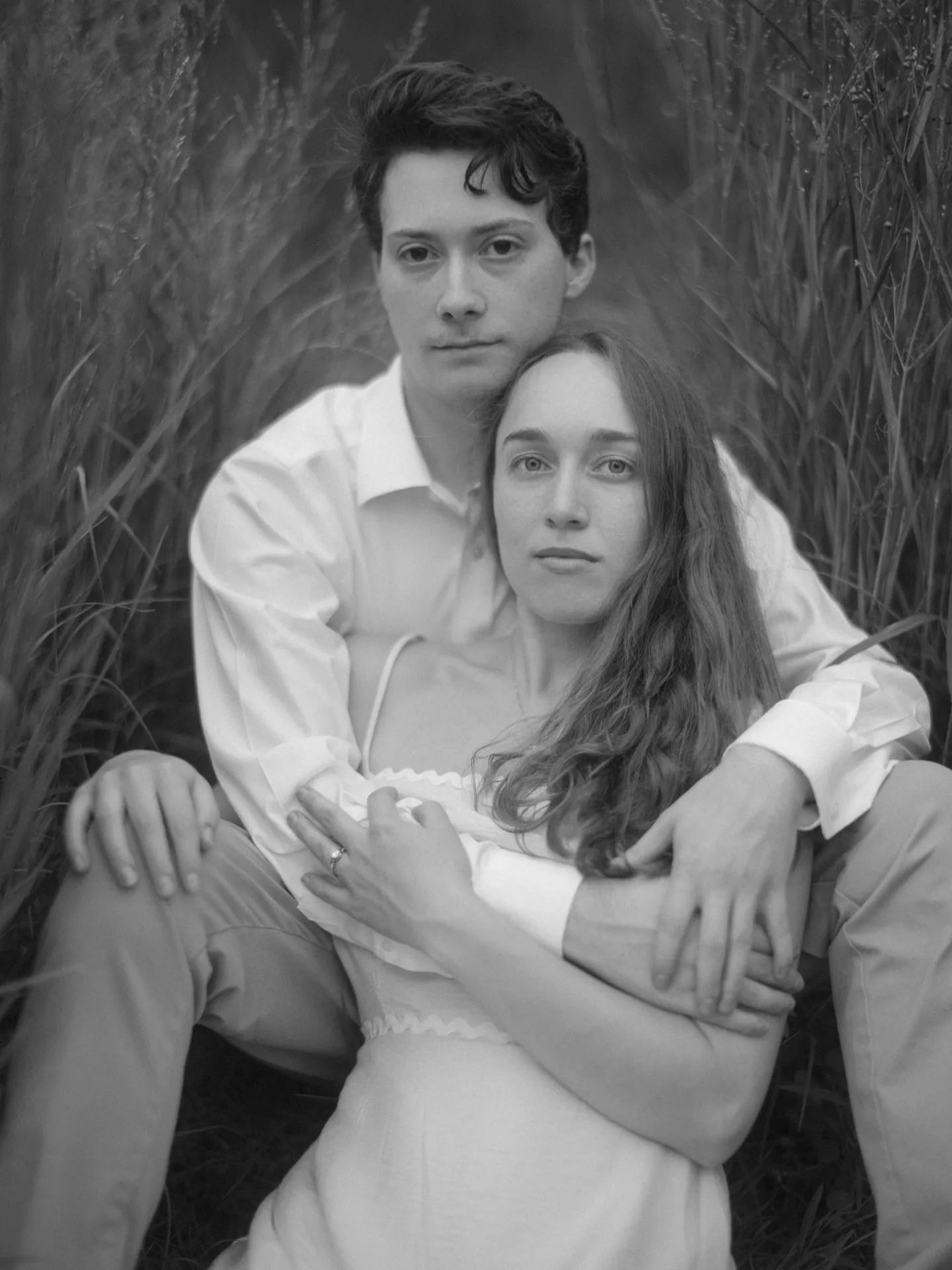 Black and white portrait of a couple seated in tall grass