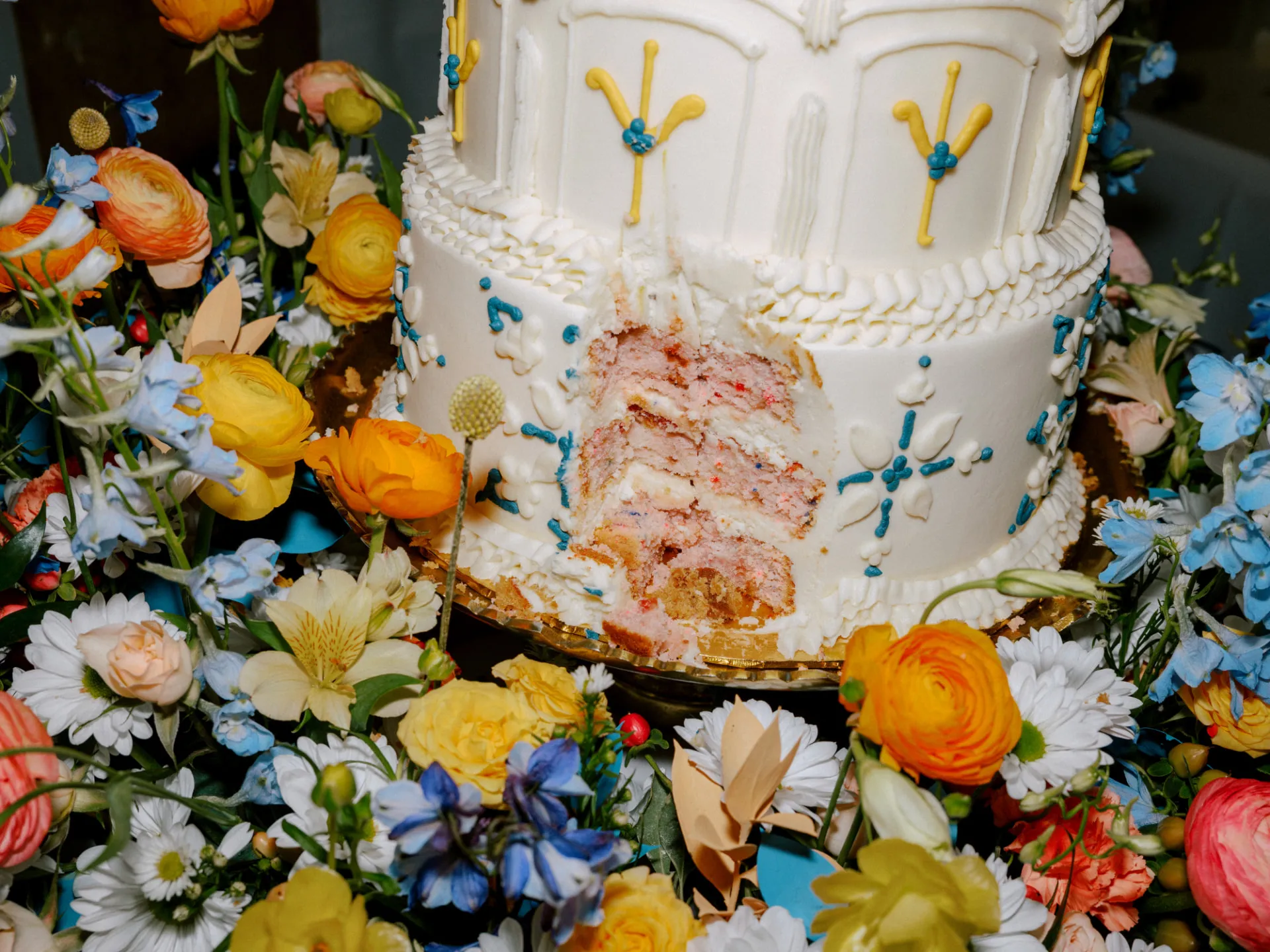 Wedding cake cut open, surrounded by wildflowers in bloom