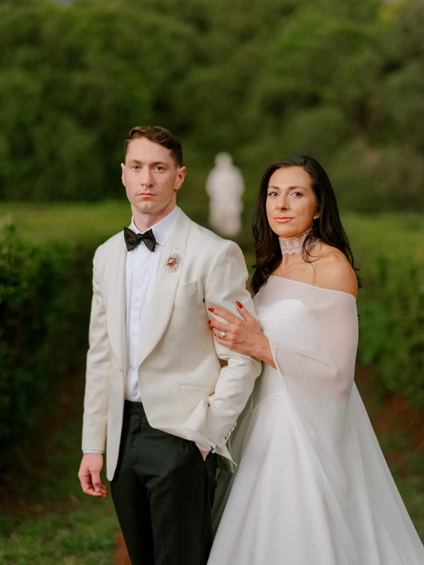 Bride and groom arm in arm in a garden at dusk