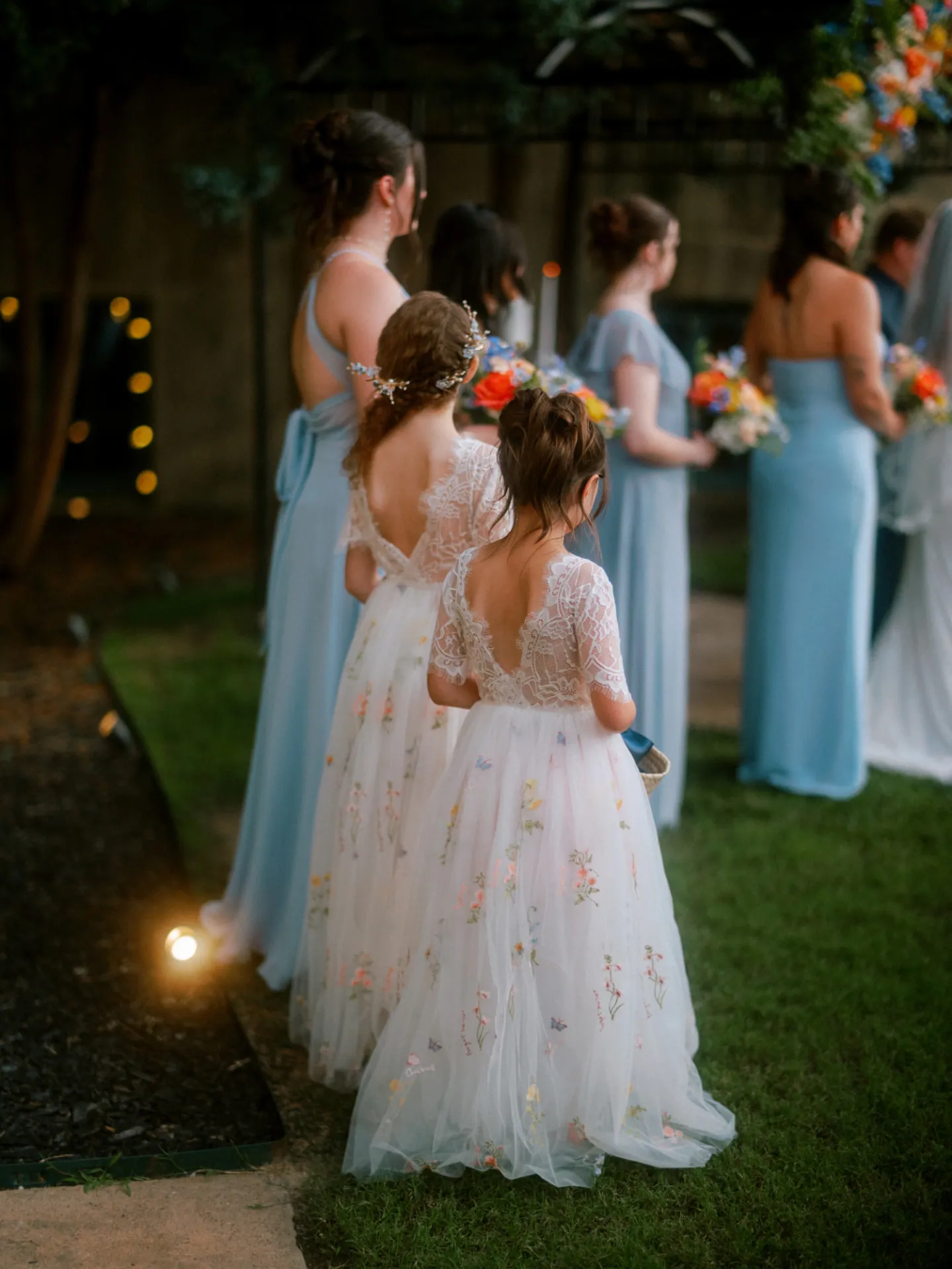 Flower girls and bridesmaids at dusk during the ceremony